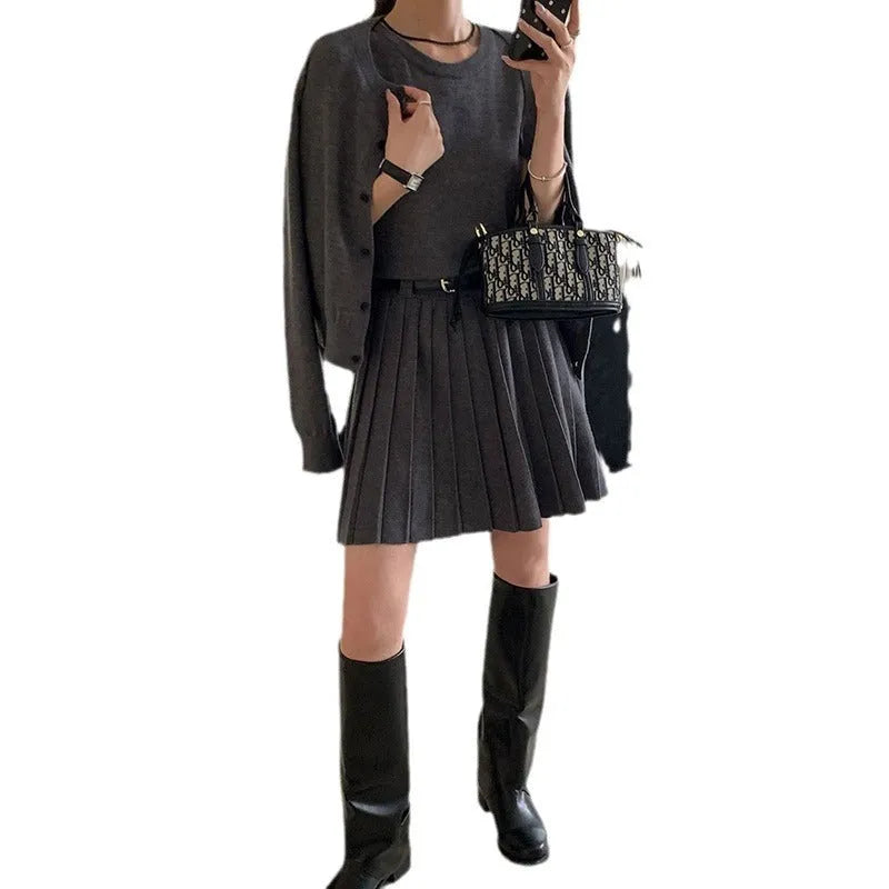 Women's grey knitted cardigan and pleated vest skirt two-piece set with a belt.
