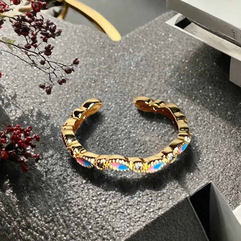 Adjustable copper ring with vintage oil dripping finish showing gourd, flower and bow design with inlaid zircon stones.