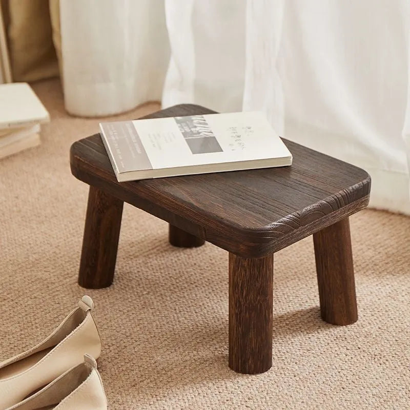 Distressed solid wood changing stool with bracket structure in a rustic finish.
