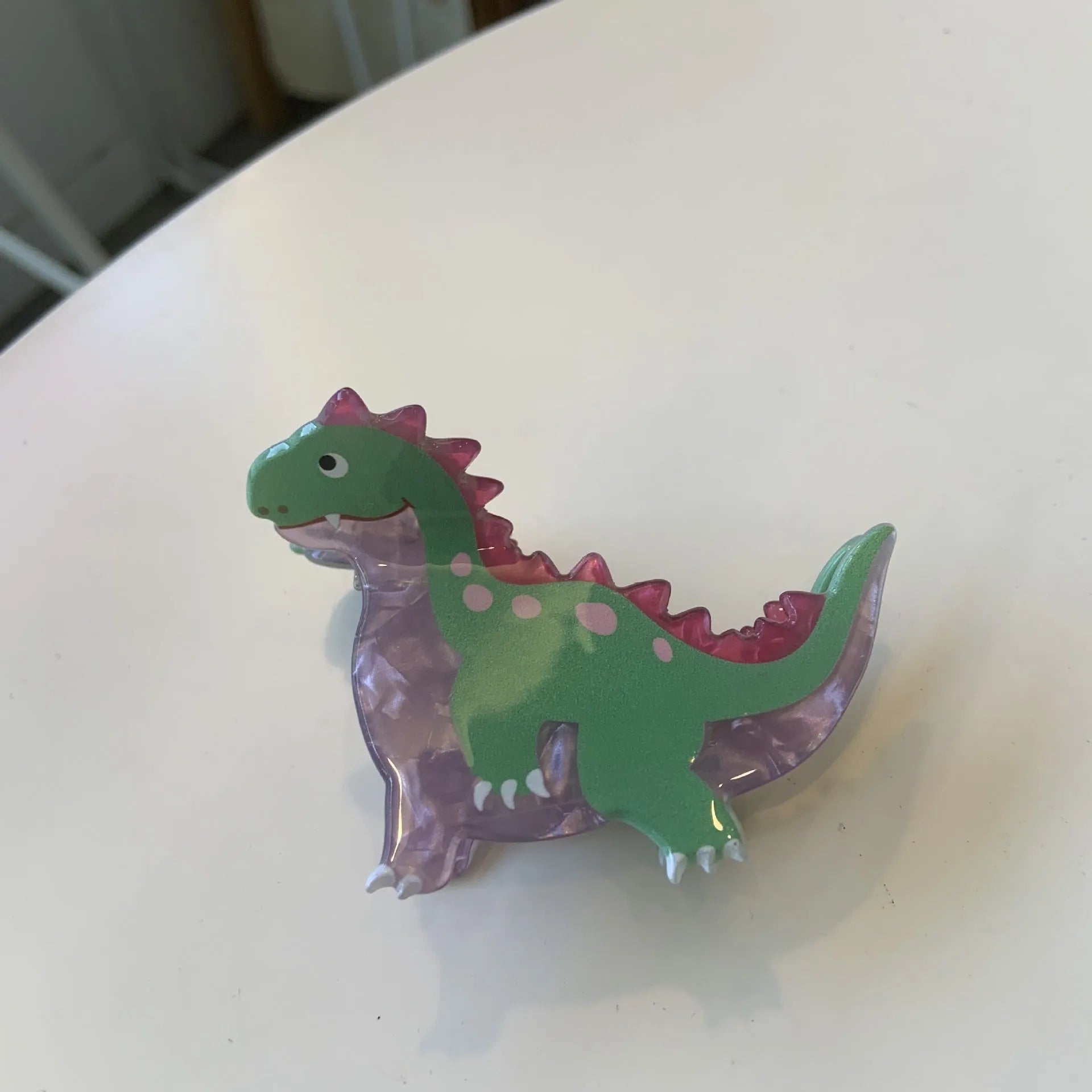A dinosaur-themed acrylic jaw hair clip for women in one of six colours, showing a cute little dinosaur design.