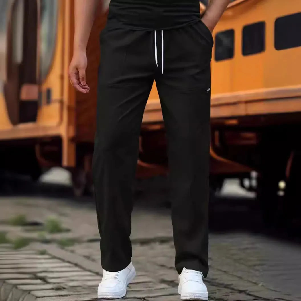 Men's light grey tapered slim-fit trousers with an elastic waistband on a hanger.