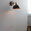 Inn Niche Nordic style wooden bedside wall lamp in walnut colour mounted on a light wall.