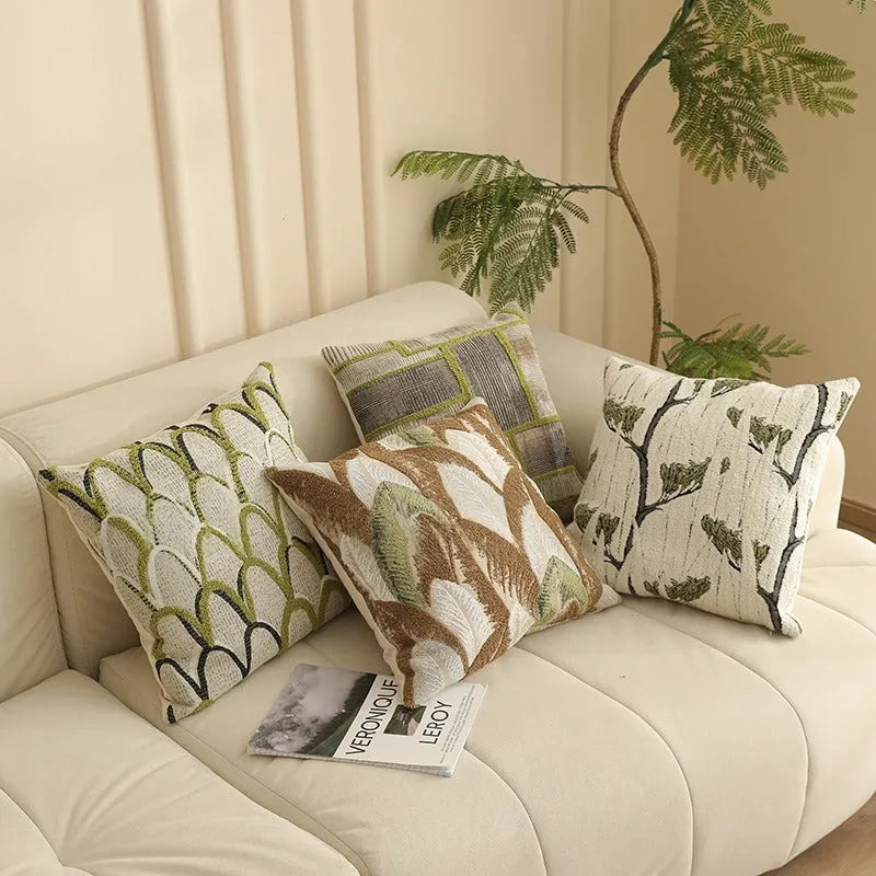 Square jacquard pillow cover with botanical pattern on a sofa, showing one of eight available colour options.