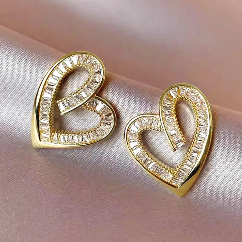Hollowed heart shape ear studs in yellow gold tone copper with inlaid zircon detail