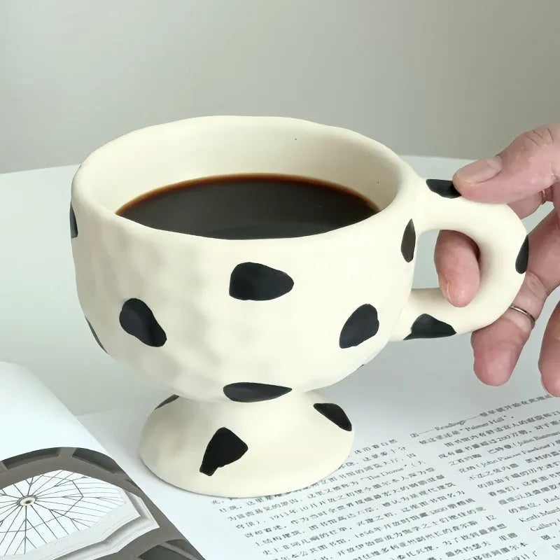 Hand-pinched irregular shaped ceramic mug in a solid colour, shown on a surface.