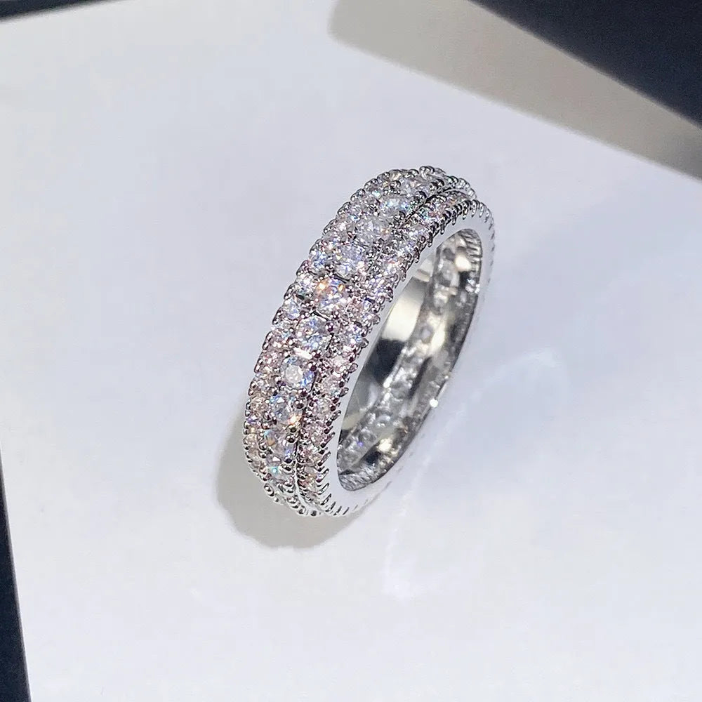A geometric unisex ring with a triangular zircon stone inlay, shown in white gold, yellow gold and white and black plating finishes.