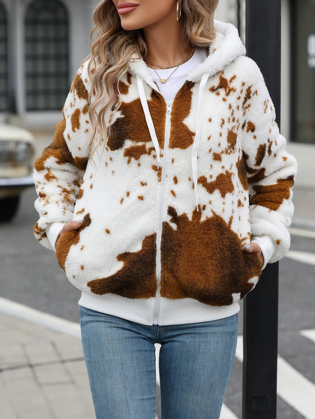 Yellow brown cow animal print hooded cardigan jacket with zip front on a hanger