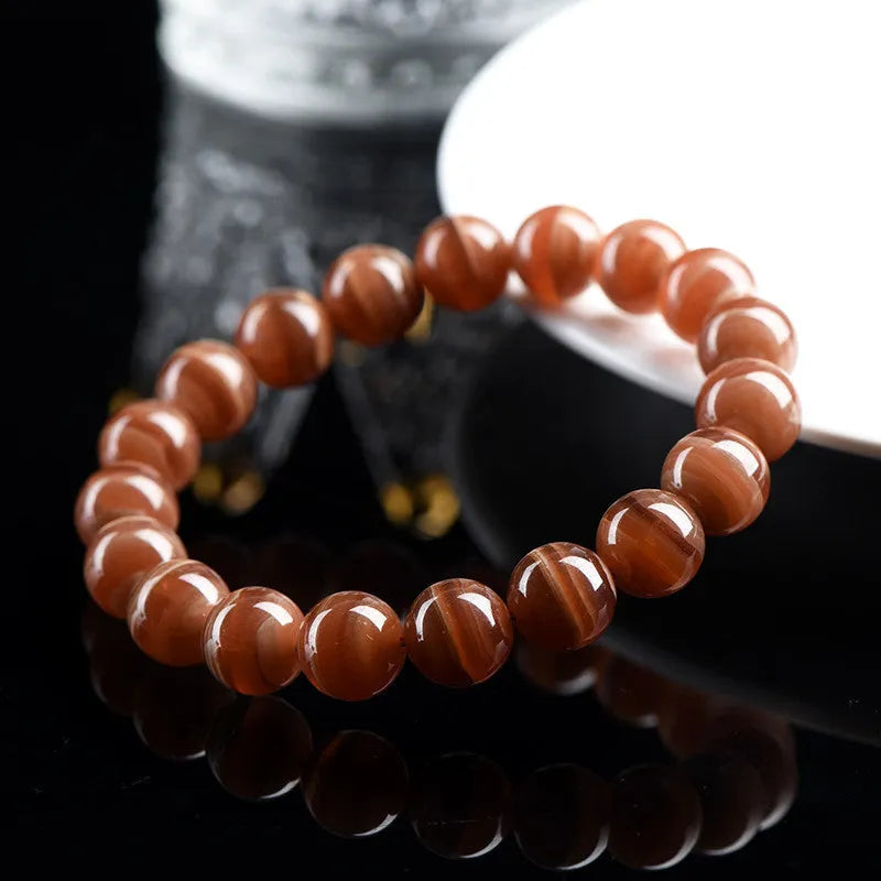 Natural old mine rhodochrosite round bead bracelet with ruyi design on a wrist.