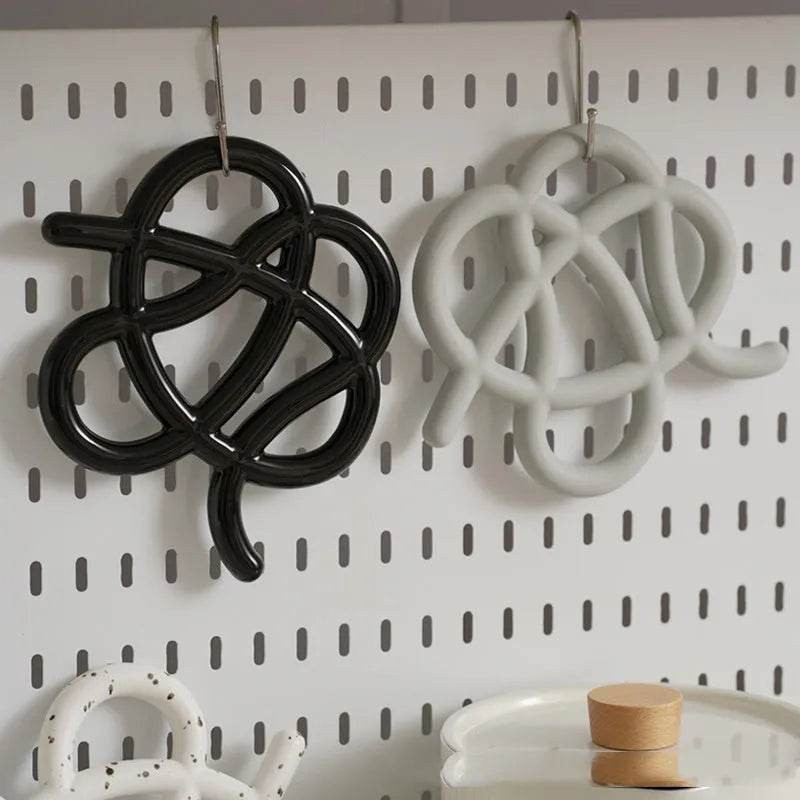Ceramic heat proof mat in an irregular shape on a wooden table.