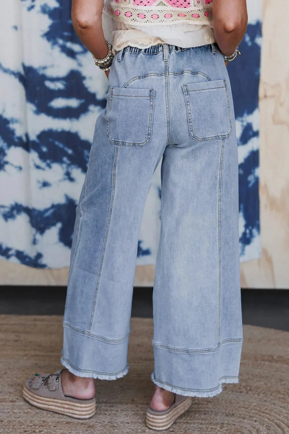 Beau blue women's wide-leg denim trousers with a drawstring waist and raw hem detail laid flat.
