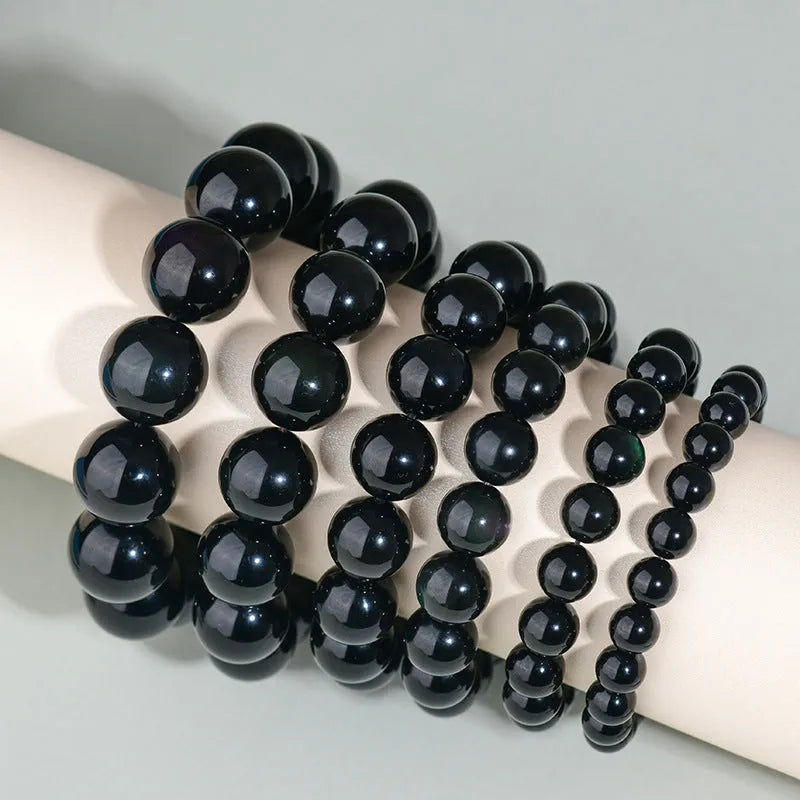 Adjustable sliding knot obsidian bracelet in hand with choice of black, rainbow eye, and silver crystal beads