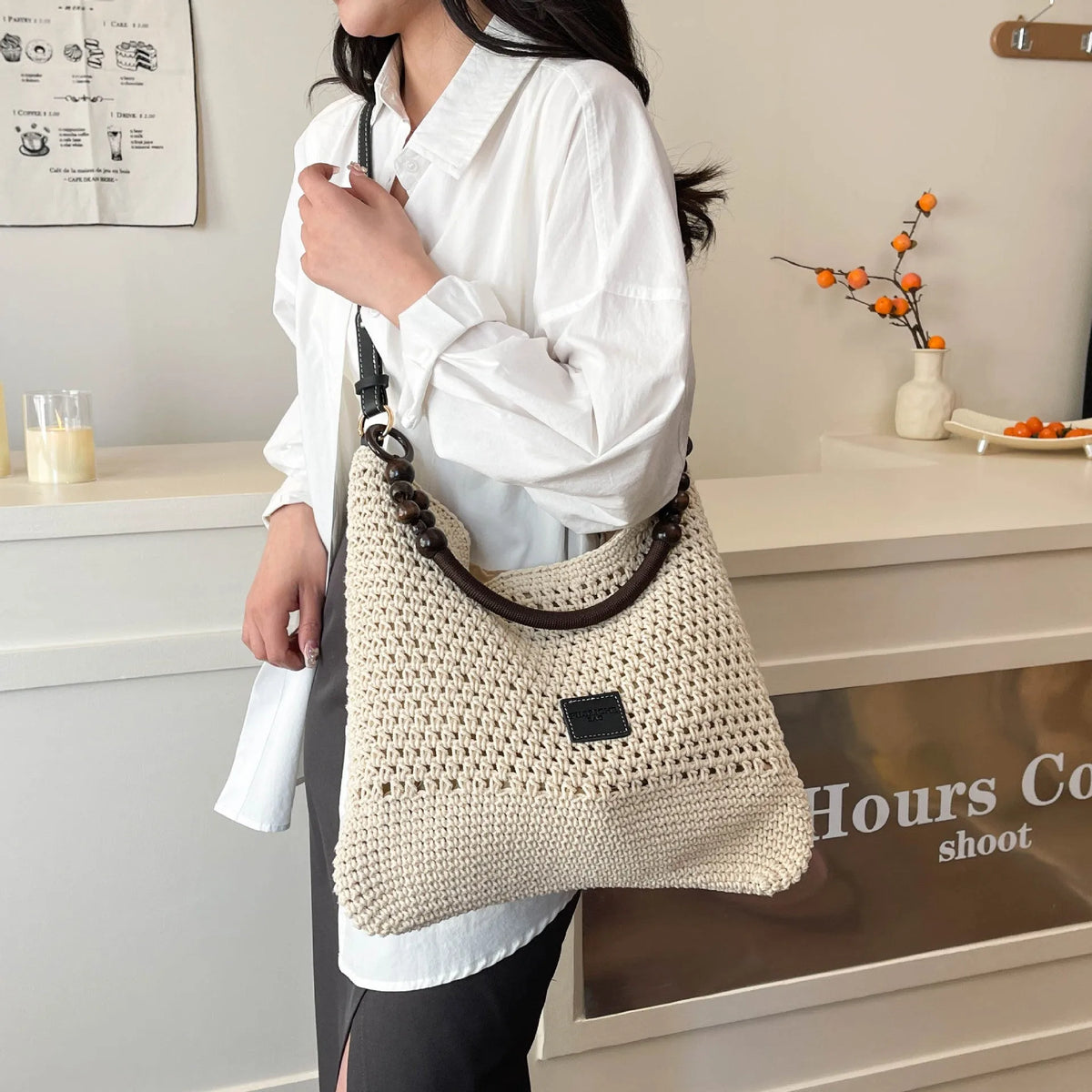 Knitted crossbody tote bag in bucket shape, shown in black with contrast stitching and a zippered internal pocket.