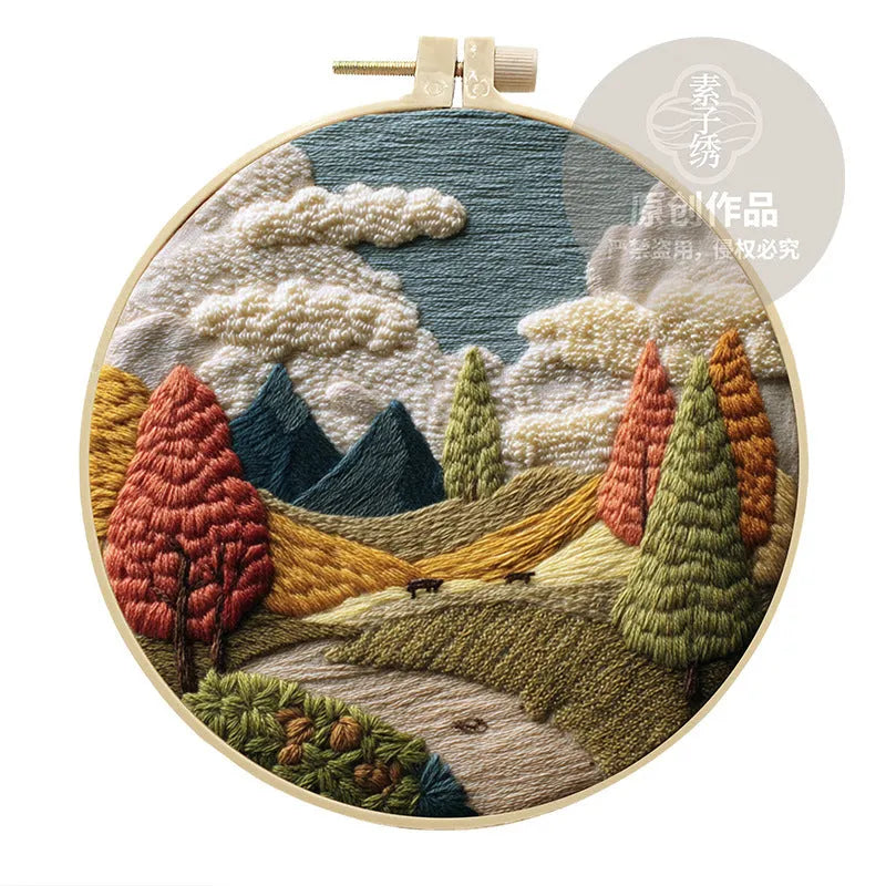DIY landscape embroidery kit with bamboo frame, printed fabric, and thread on a table