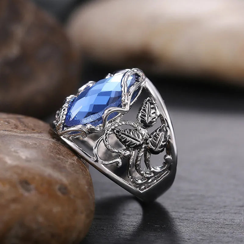 Blue crystal inlay horse eye-shaped geometric alloy ring for women on a plain background.