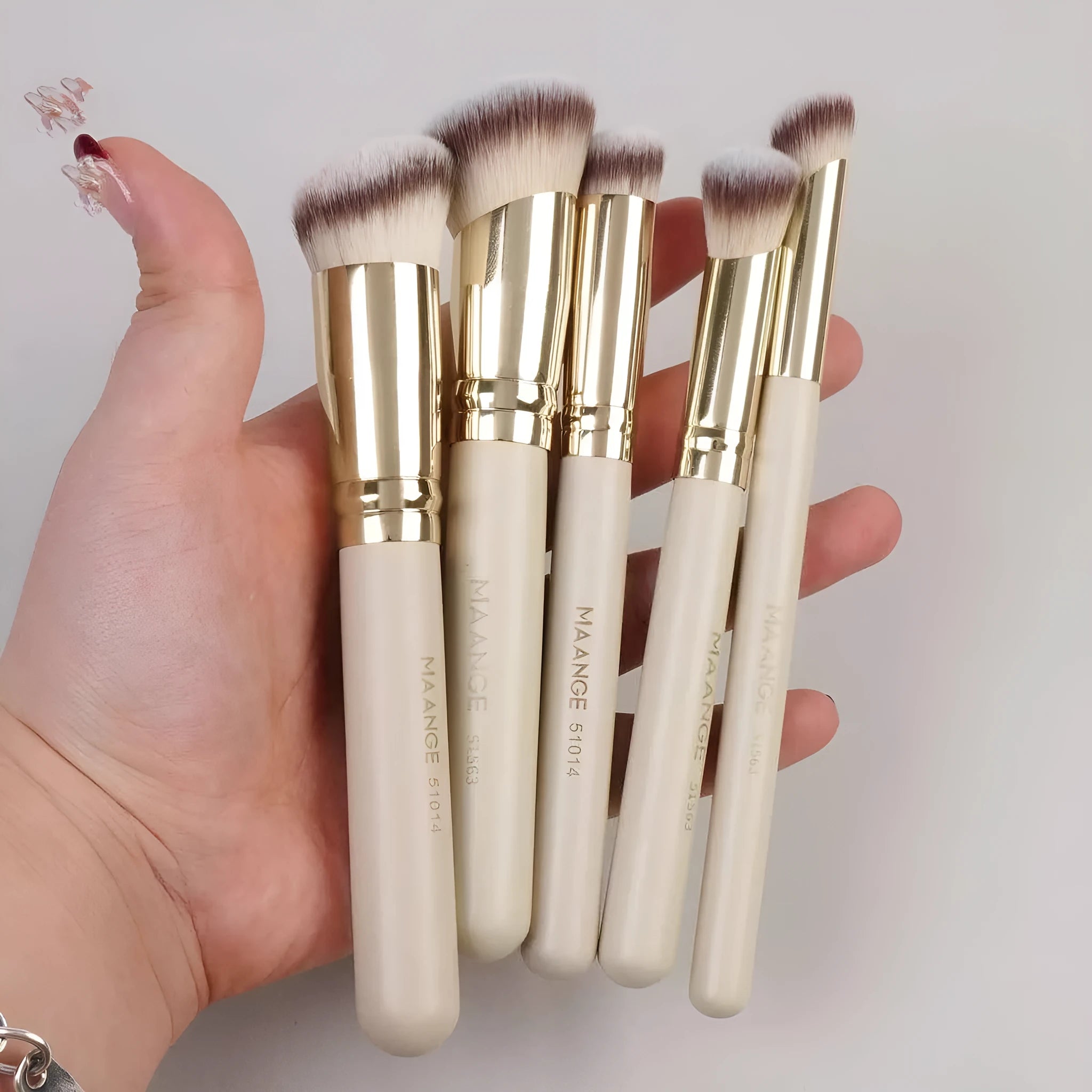 Five apricot-coloured angled makeup blush brushes with synthetic bristles arranged together