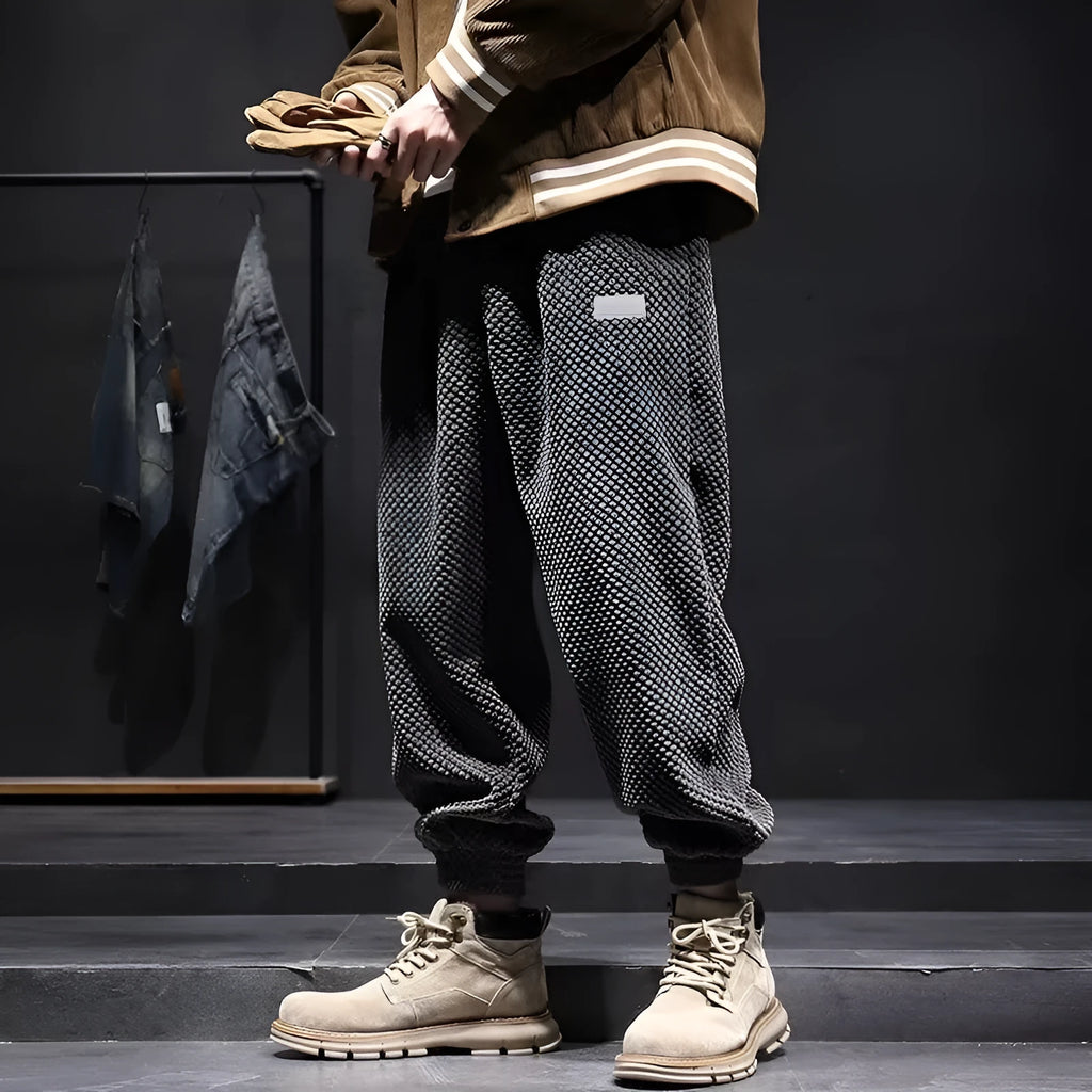 Man wearing grey straight-leg casual sweatpants with an ankle-tied design detail.