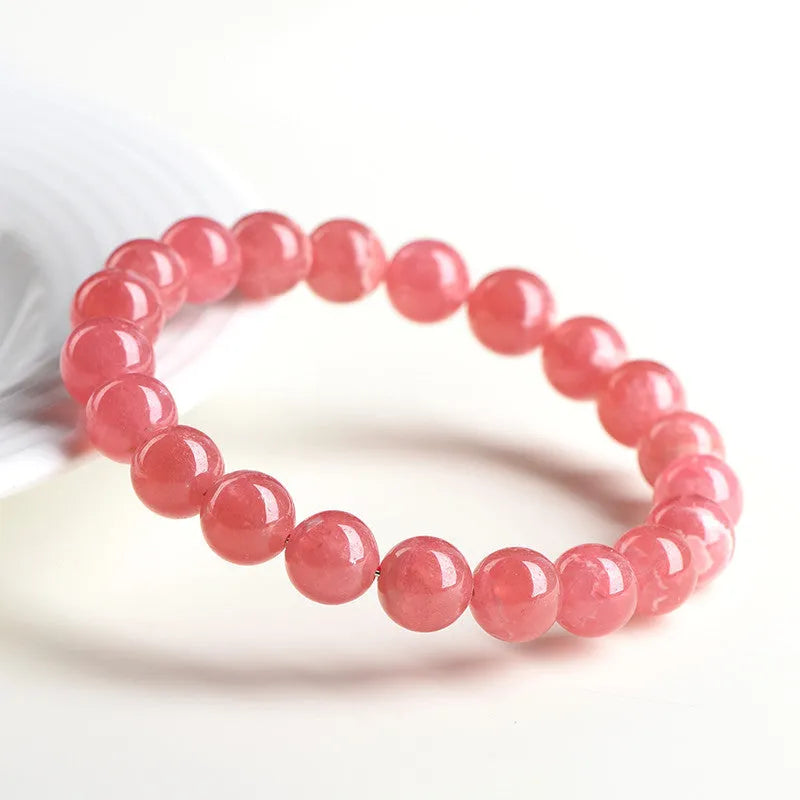 Women's red rhodochrosite crystal bracelet with geometric beads and a Longevity Lock charm.