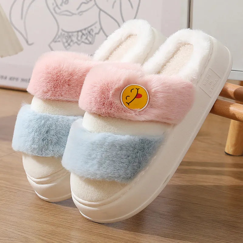 Pink and green cartoon thermal cotton slippers with plush upper and cashmere lining on a wooden floor.