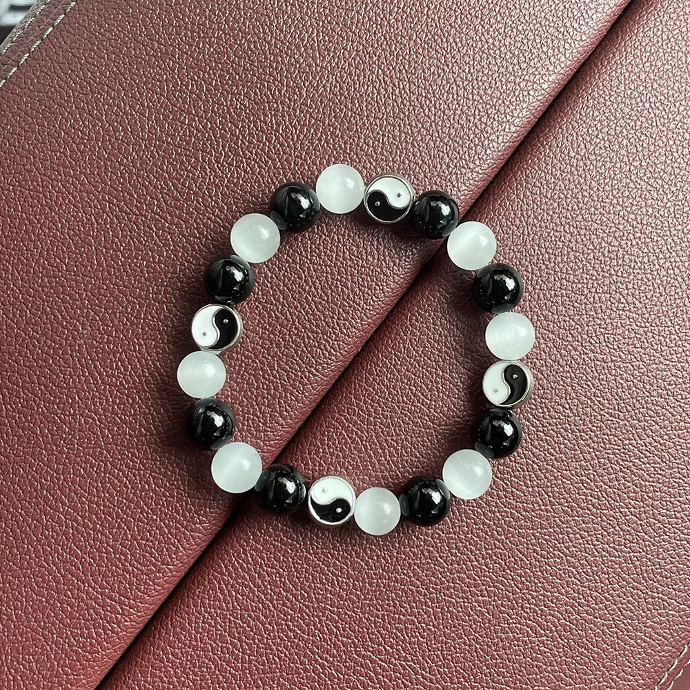 Close-up of a polished opal Tai Chi beaded bracelet with black agate ornamentation on a wrist.