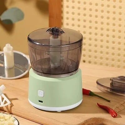 White or light green USB rechargeable mini electric meat grinder with transparent cup on anti-slip pad.
