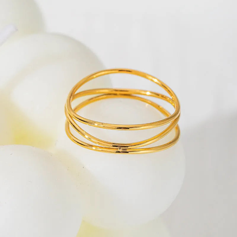 Geometric three-layer coil gold ring on a finger, showing titanium steel construction.