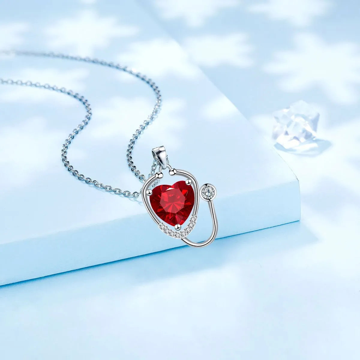 Women's fashion necklace with a copper wings cross stethoscope pendant featuring red diamond detail.