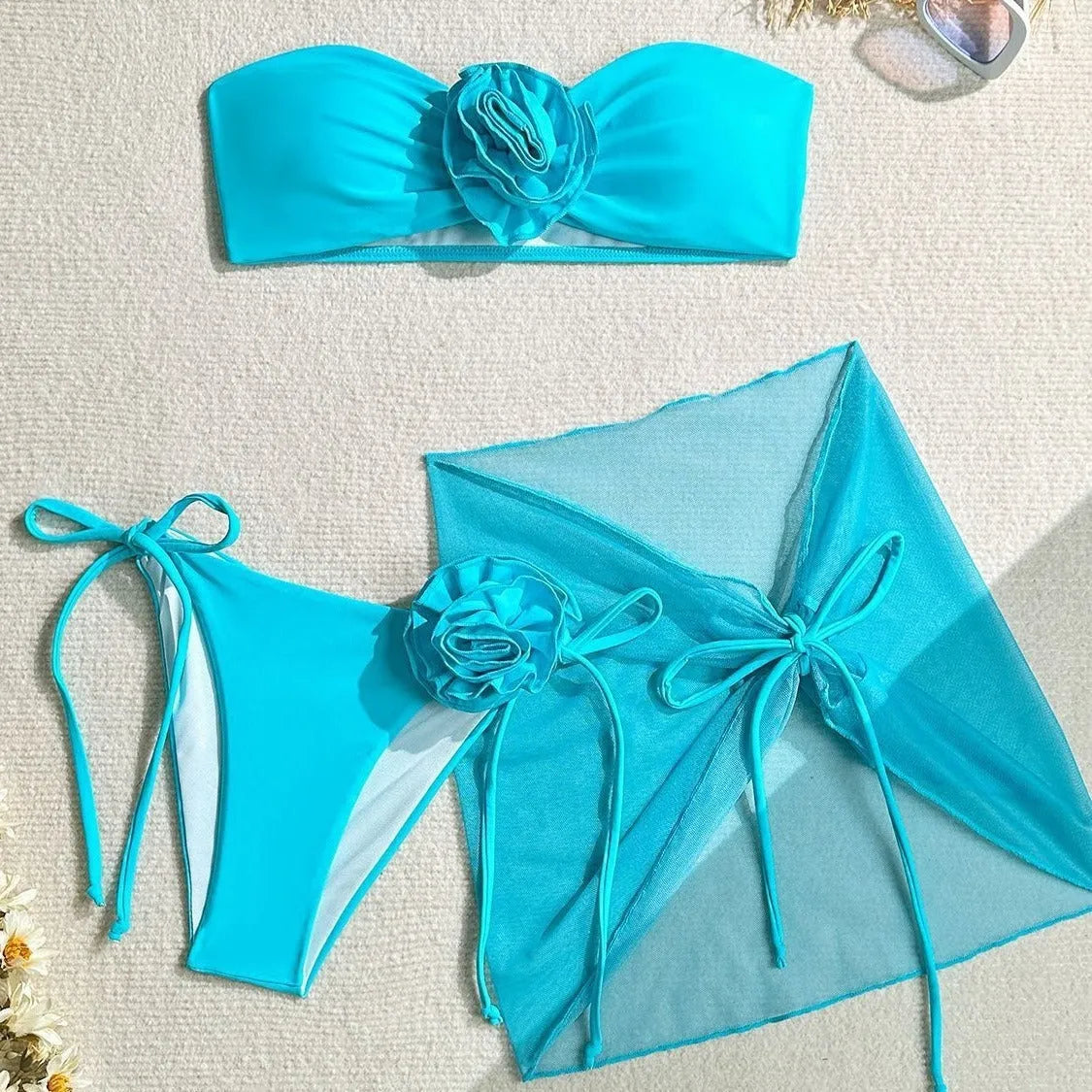 Women's pink tube top swimsuit with a large 3D flower, matching bottoms, and a skirt laid flat.