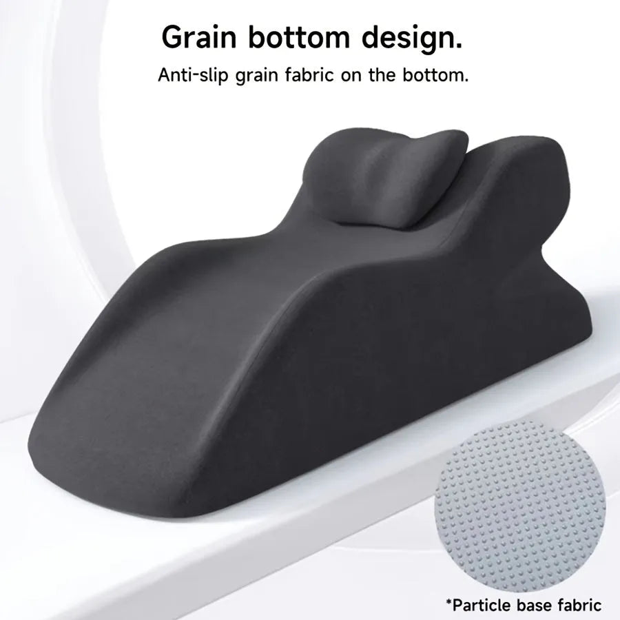 A flat stomach sleeper pillow shown on a bed, designed for prone sleeping and reading.