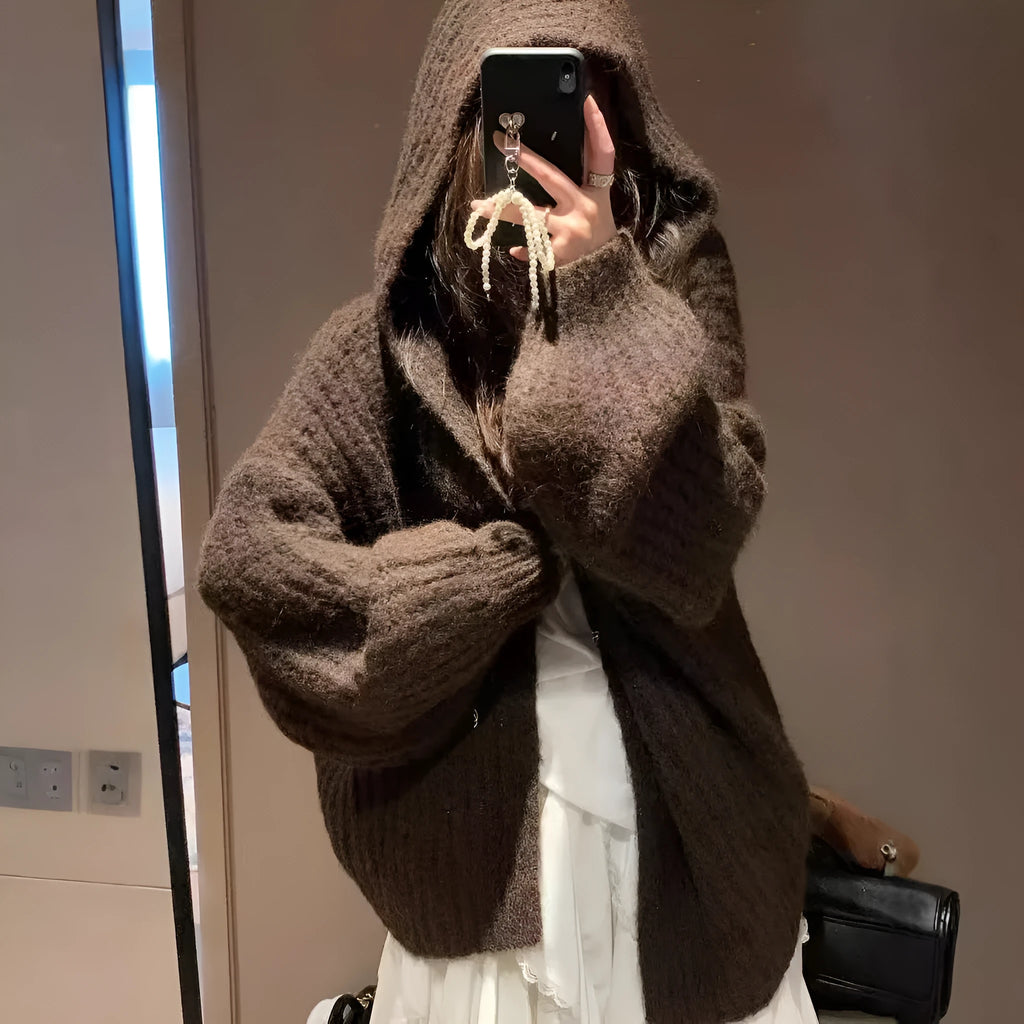 A woman wearing a thick, loose-fit hooded cardigan sweater in a milky white colour.
