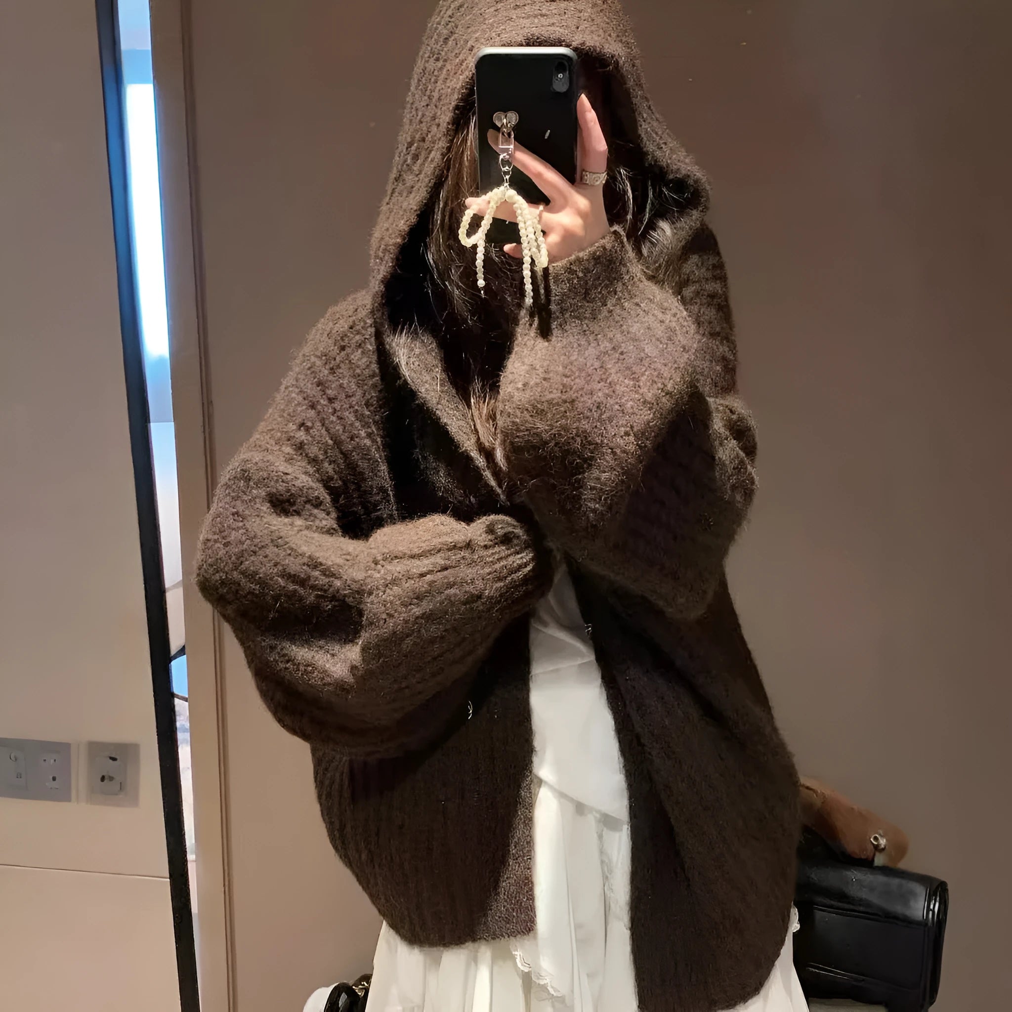A woman wearing a thick, loose-fit hooded cardigan sweater in a milky white colour.