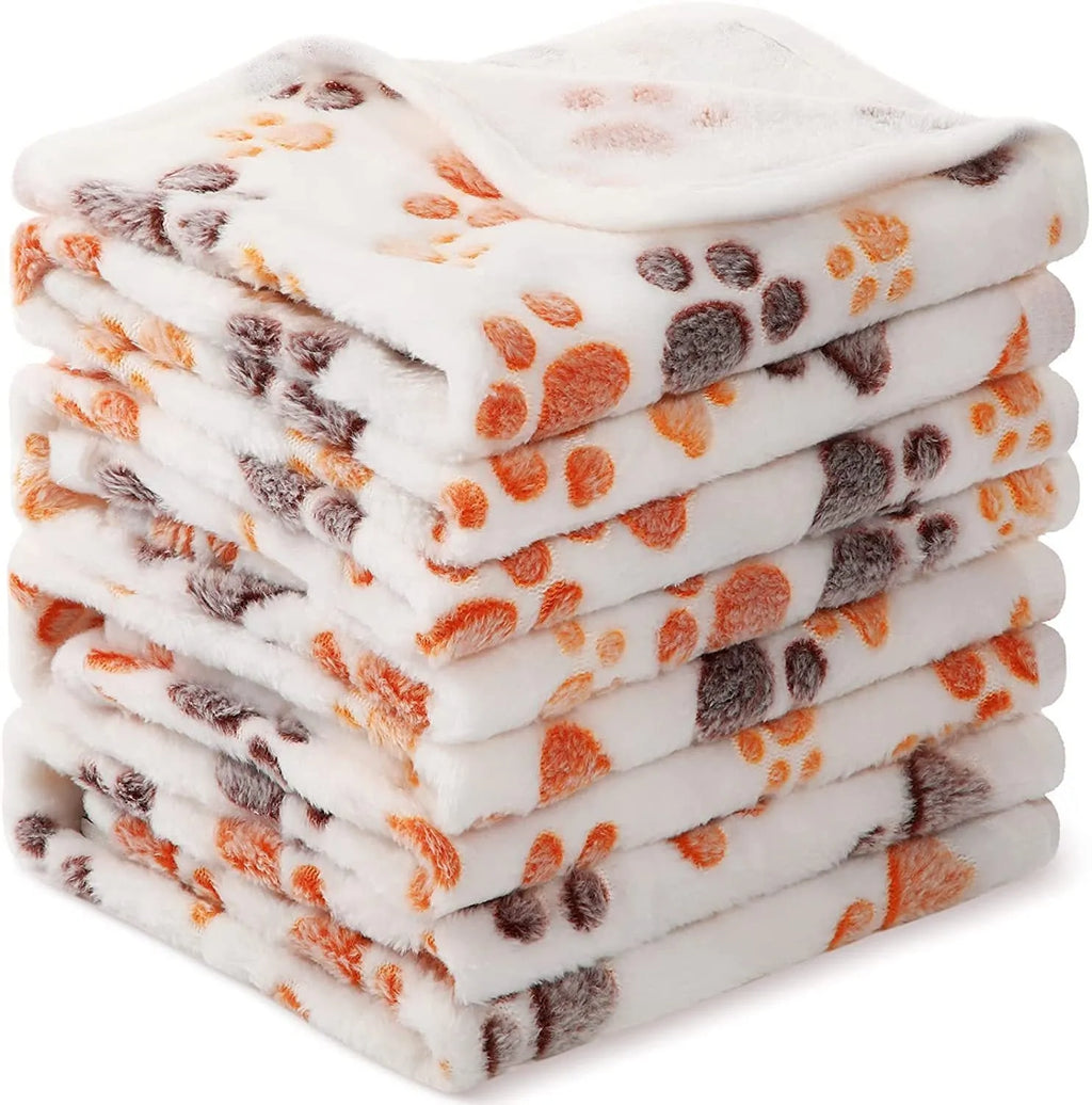 Soft coral fleece dog blanket with paw print design shown in beige colour on a dog bed.