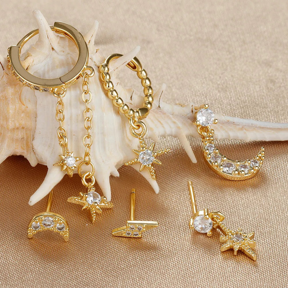 Set of six gold electroplated earrings with zircon studs and chain tassels on a flat surface.