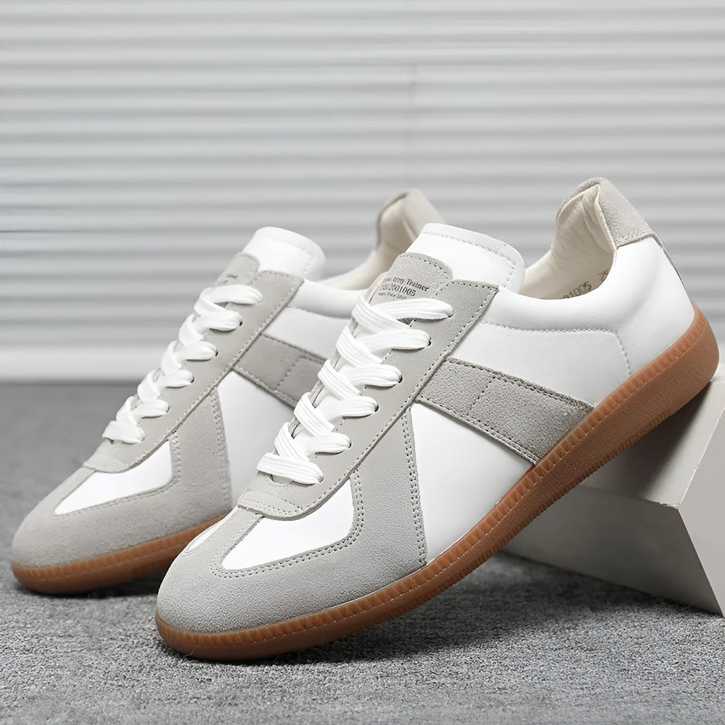 White low-top retro unisex sneakers with round toe and lace-up front on a plain background.