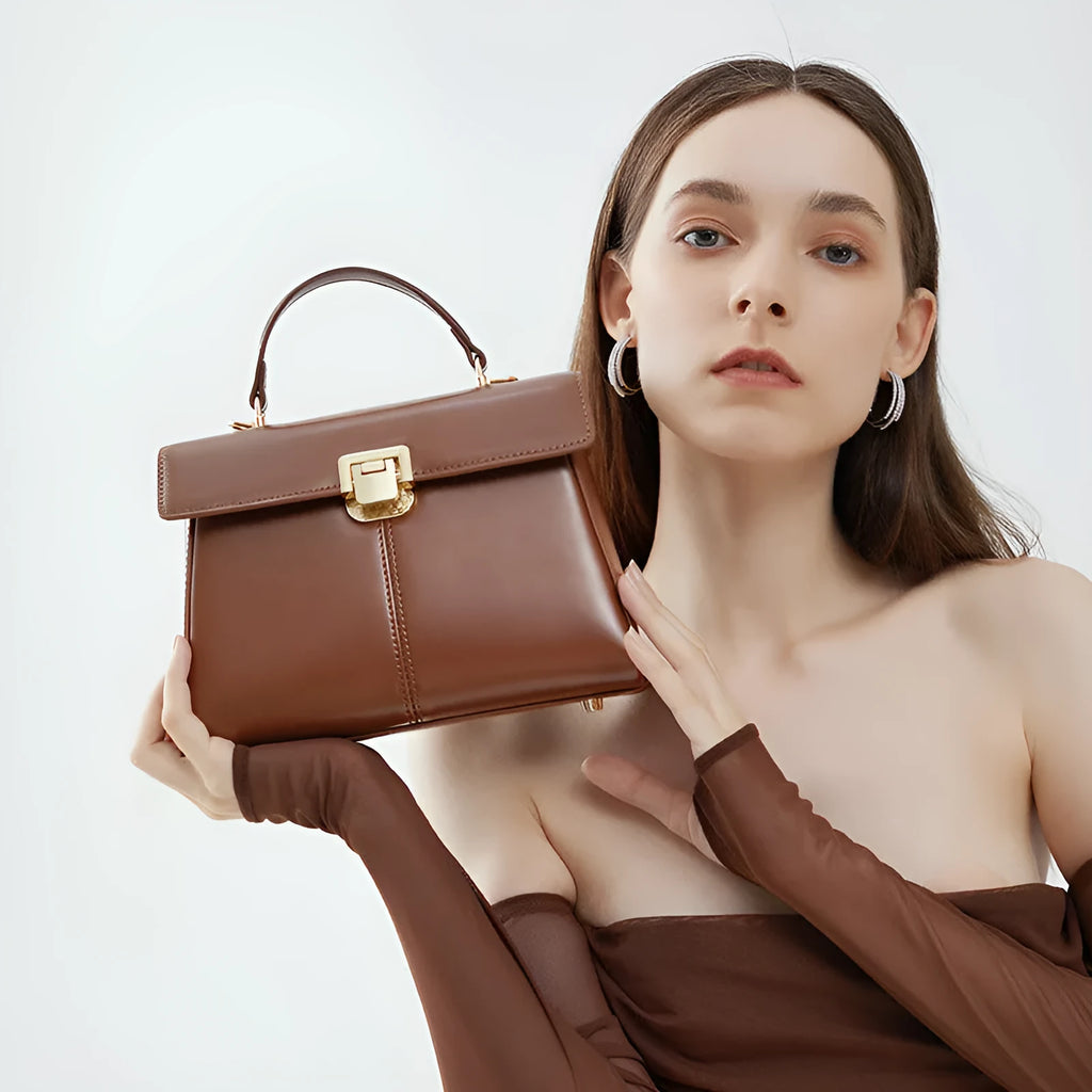 Women's black leather shoulder bag with vachette clasp showing horizontal square shape and shoulder strap