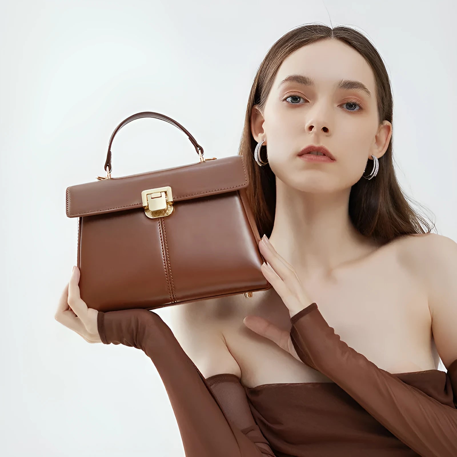 Women's black leather shoulder bag with vachette clasp showing horizontal square shape and shoulder strap