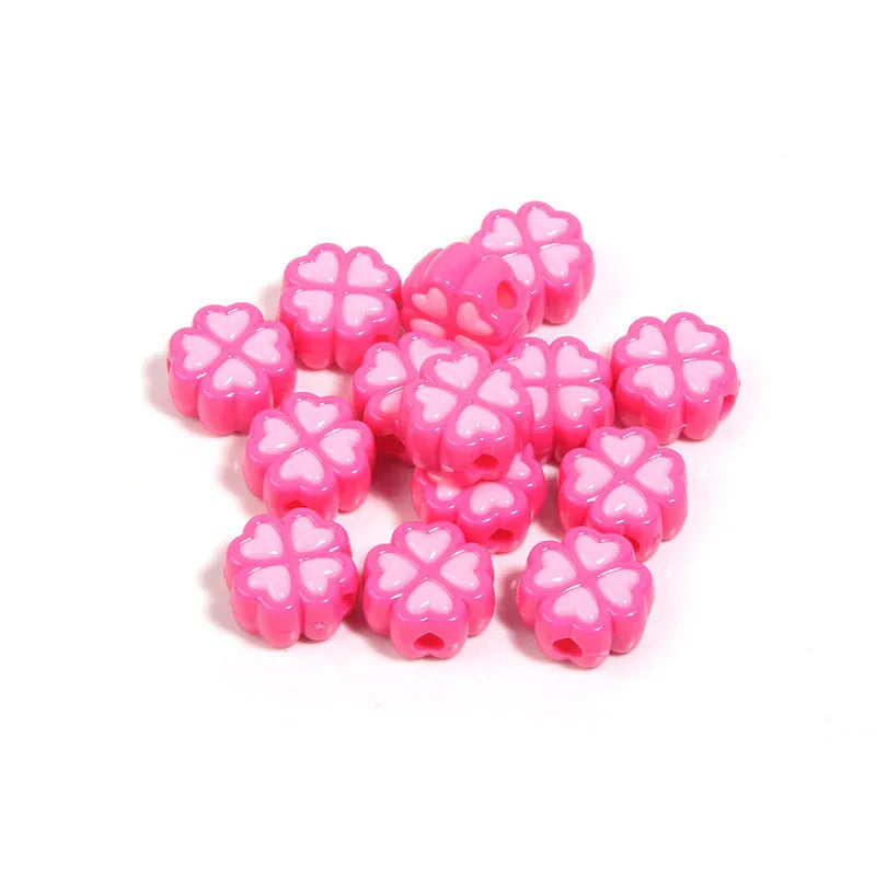 Assortment of frosted acrylic love clover beads in mixed colours on a white background.