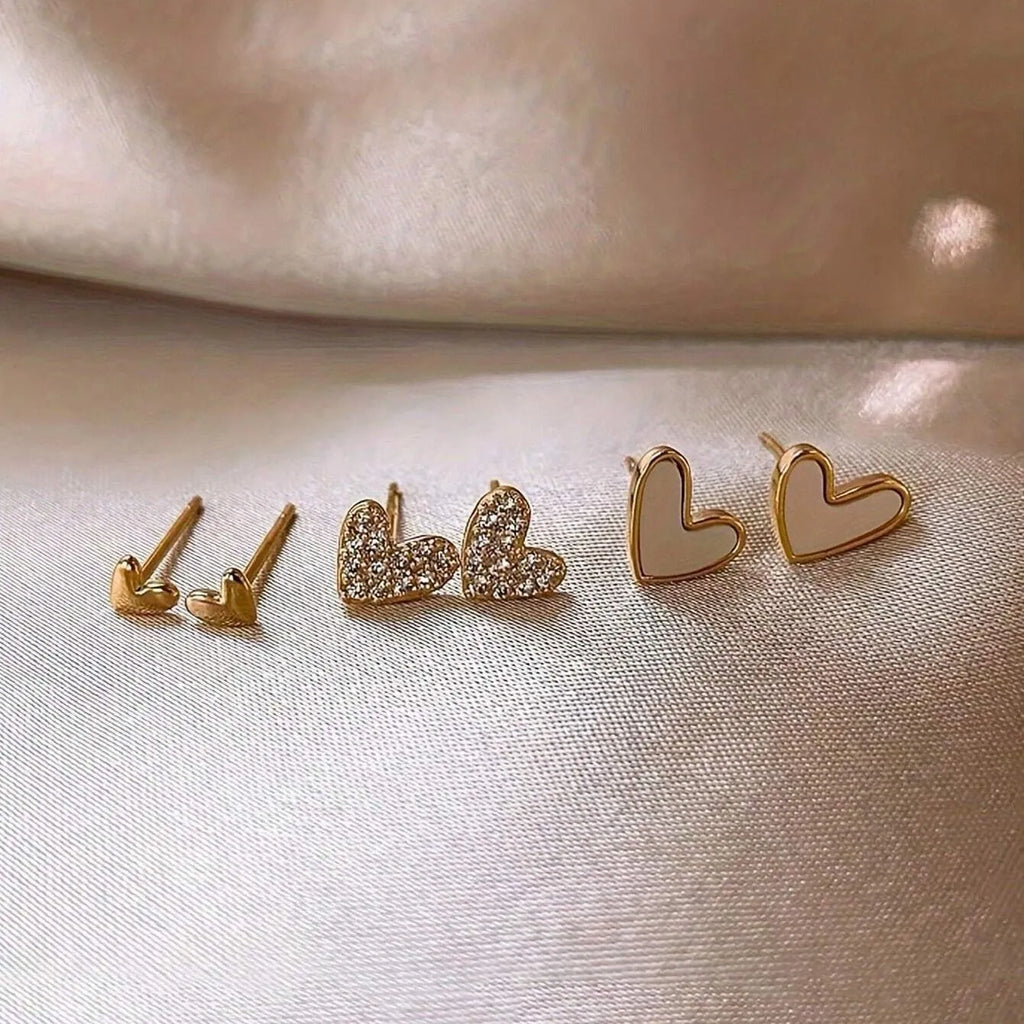 Three pairs of heart-shaped alloy earrings with electroplated finishes in gold, black, white, or pink colours.