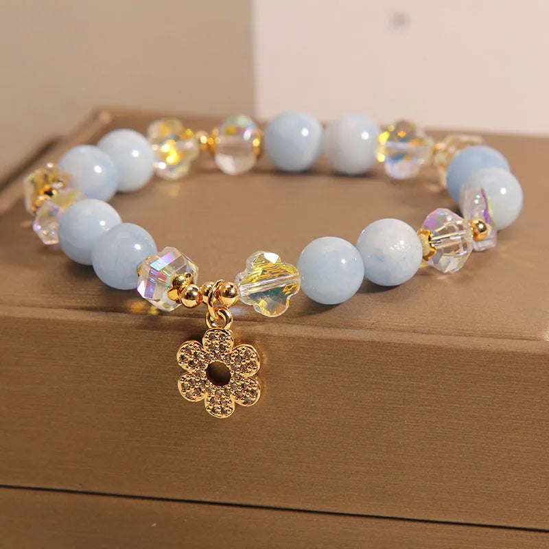 Women's aquamarine crystal bracelet with a four-leaf clover charm and pearl accents on a band.