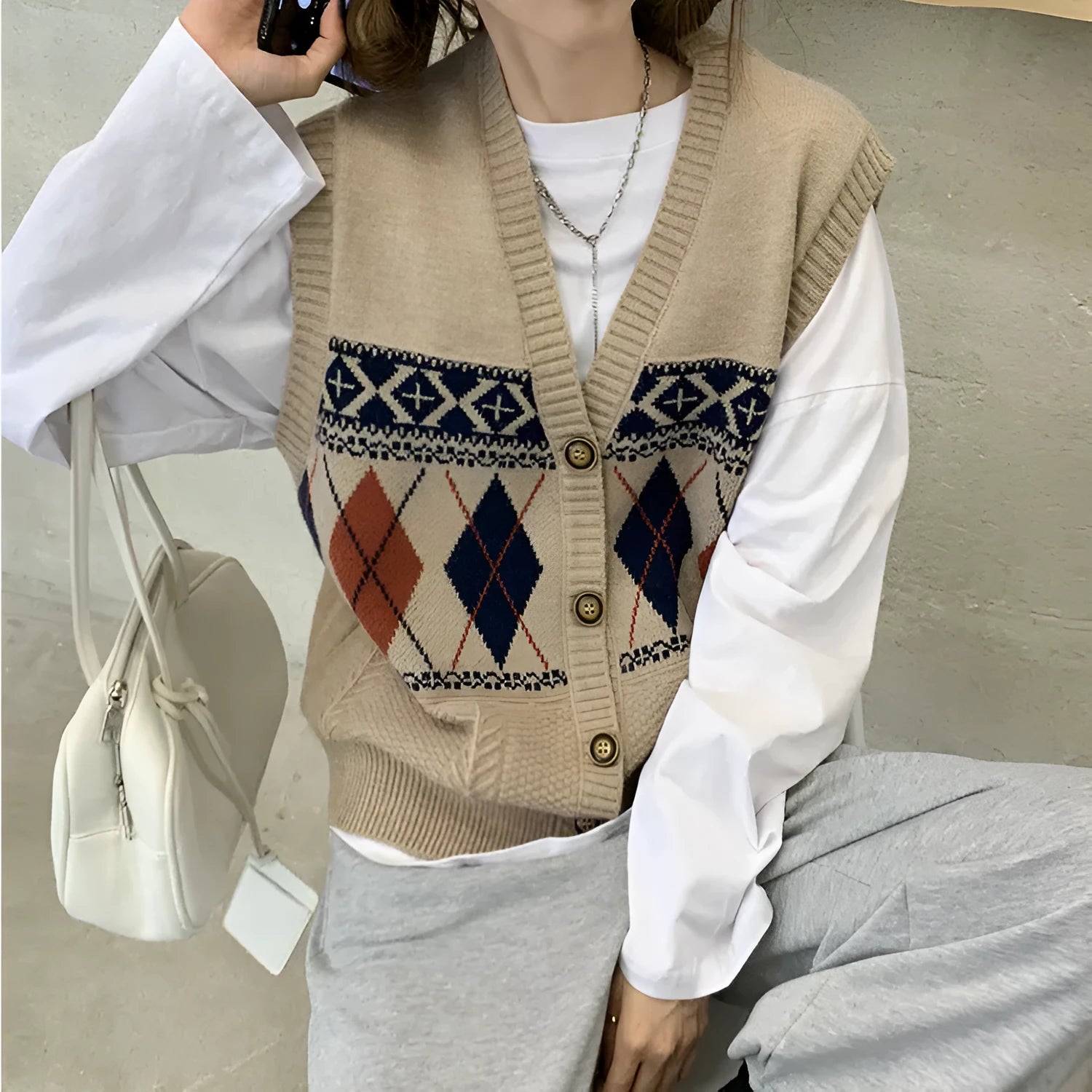 Diamond plaid pattern sleeveless cardigan top in khaki colour, laid flat.