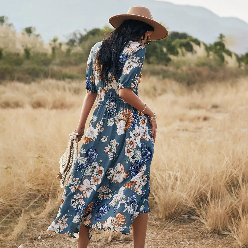 Yellow floral print summer dress on a woman, showing V-neck, short sleeves, elastic waist, and a flowing mid-length skirt.