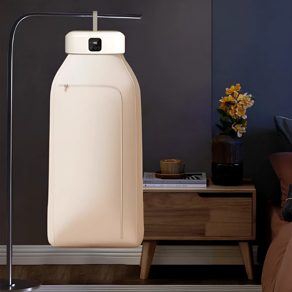 White cylindrical portable mini clothes dryer with remote control on a table.