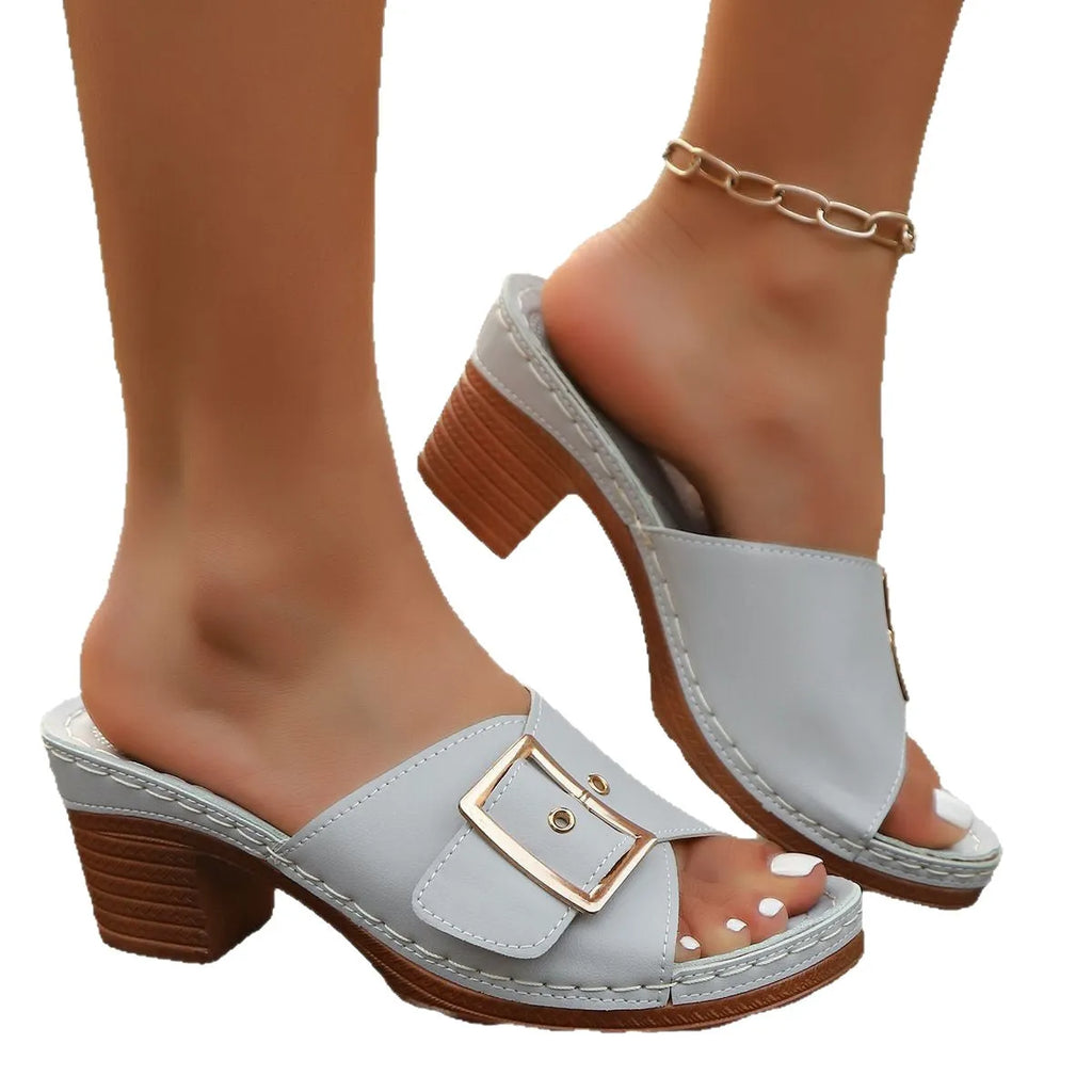 Women's black slippers with a chunky heel, metal buckle strap, and round toe on a rubber sole.