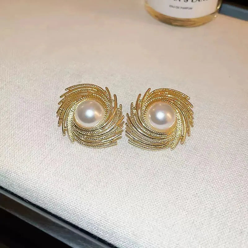 A pair of vintage-inspired pearl-coloured floral drop earrings with an irregular design on a white background.