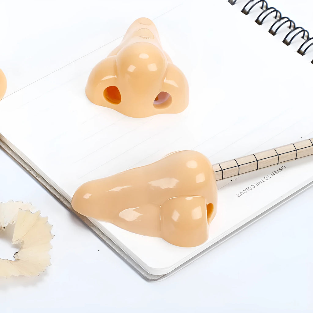 Flesh colour plastic geometry pencil sharpener with big nostril design on a white background.