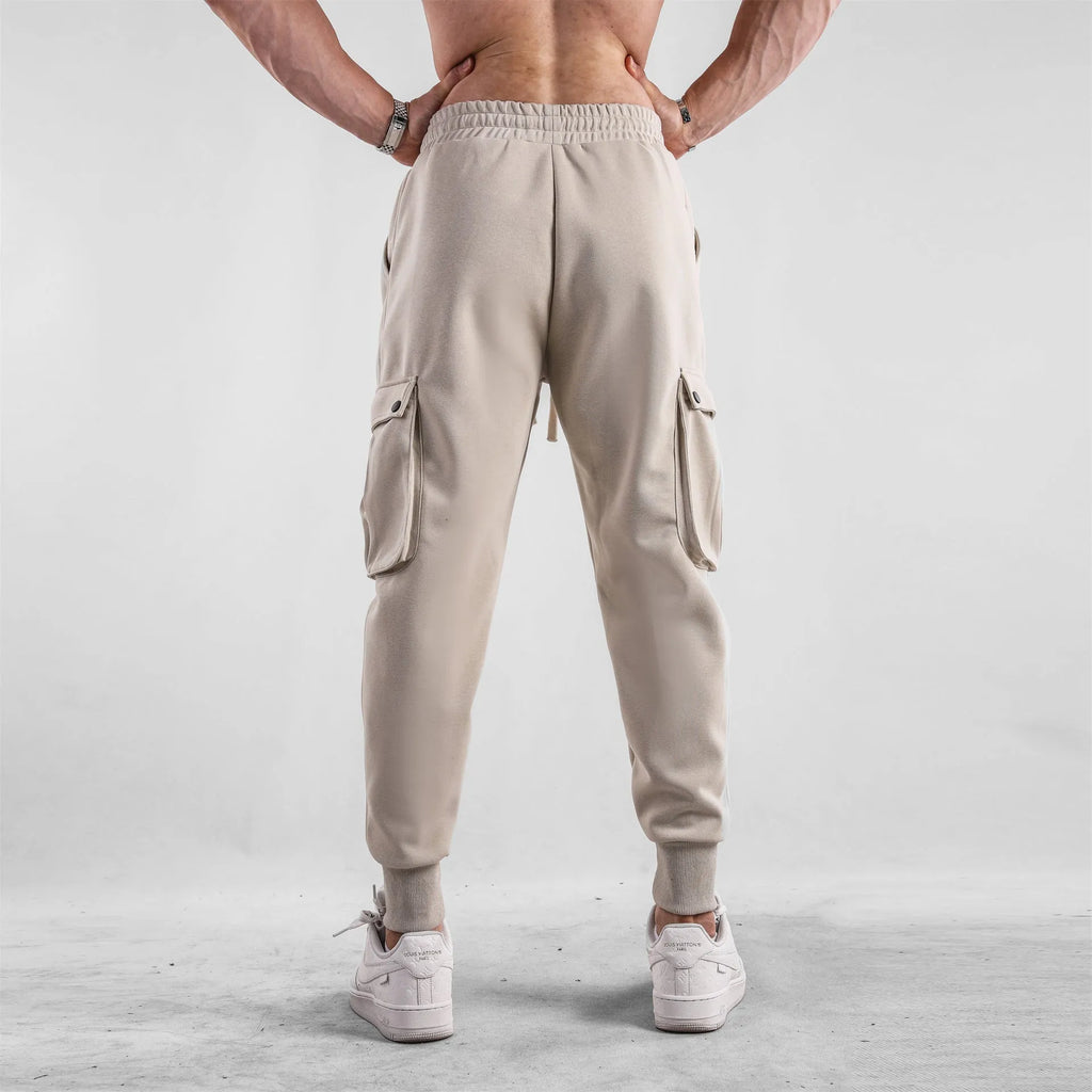 Men's loose cotton trousers with ankle ties and multiple pockets in a light grey colour