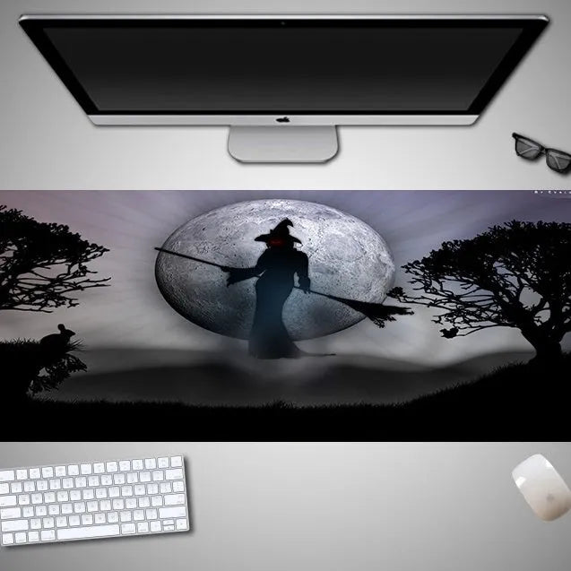 Oversized rectangular Halloween-themed mouse pad on a desk, showing one of 28 graphic designs.