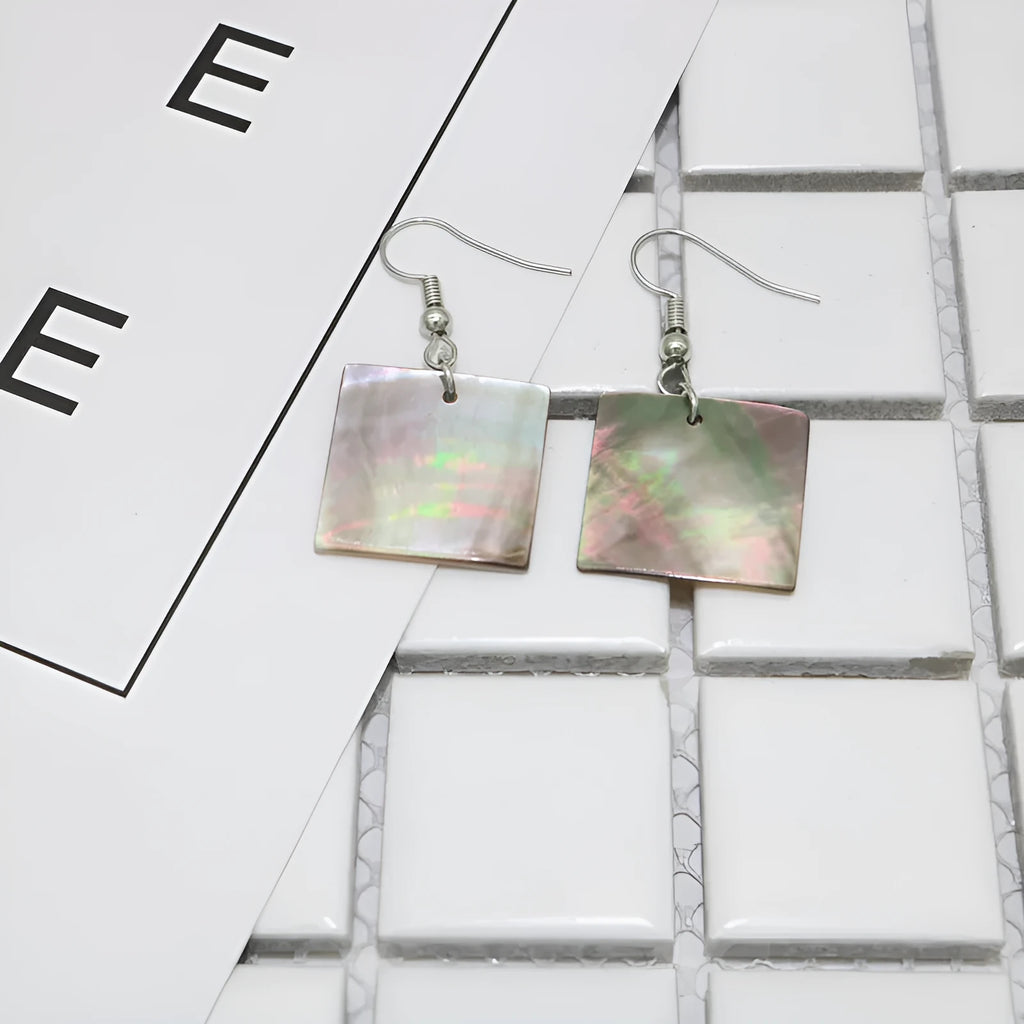 Handmade women's shell earrings in rectangular and square geometric shapes on a neutral background.