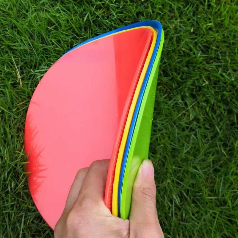 Yellow TPE football training marker disc lying flat on grass, 23cm diameter.