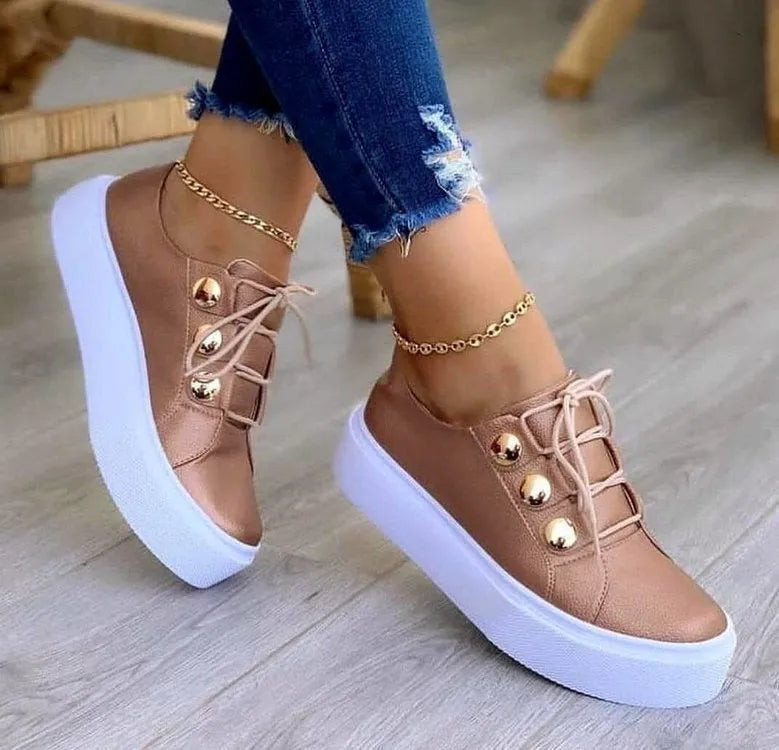 Women's white lace-up flats sneakers with round toe and metallic rivet decoration on the side.