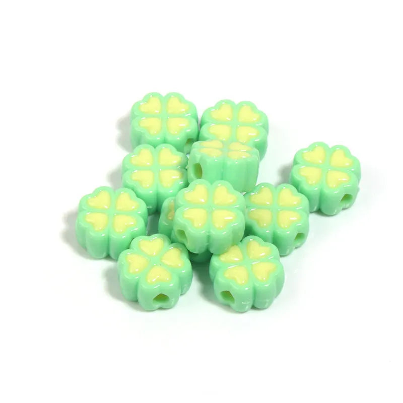 Assortment of frosted acrylic love clover beads in mixed colours on a white background.